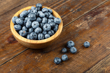 Freshly picked blueberries in wooden bowl on wooden background.  Concept of healthy and dieting eating.