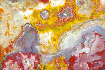 Obraz na płótnie Canvas A cross section of the agate stone with quartz geode. Multicolored silica bands colored with metal oxides are visible. Macro photography of the surface of the cut. Origin: Atlas mountains, Morocco.