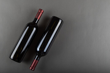 Naklejka premium A corked two bottle of red wine on a gray office. Alcoholic drink. Winemaking concept. Space for text.