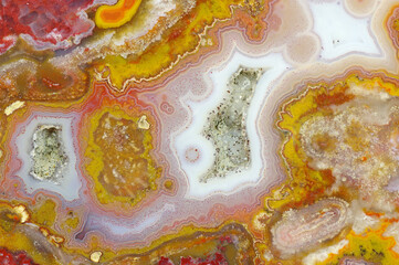 A cross section of the agate stone with quartz geode. Multicolored silica bands colored with metal oxides are visible. Macro photography of the surface of the cut. Origin: Atlas mountains, Morocco.