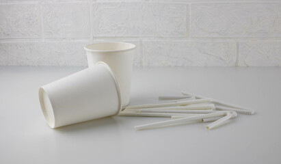 White disposable paper cups and straws on the table.