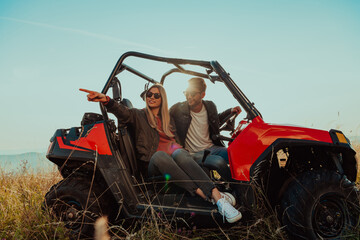 Young happy excited couple enjoying beautiful sunny day while driving a off road buggy car on...