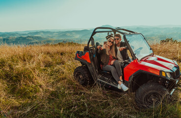Young happy excited couple enjoying beautiful sunny day taking selfie picture while driving a off...
