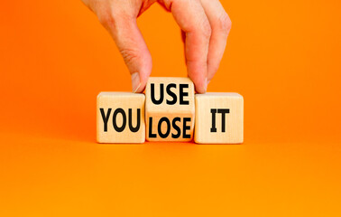 You use or lose it symbol. Concept word You use or lose it on wooden cubes. Beautiful orange table...