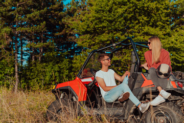 Young happy excited couple enjoying beautiful sunny day while driving a off road buggy car on mountain nature