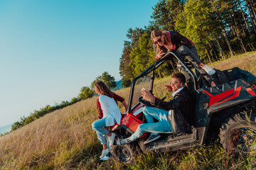 Group young happy people enjoying beautiful sunny day while driving a off road buggy car on mountain nature