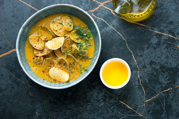 Cream-soup with chickpeas and vongole on a dark-olive marble background, horizontal shot with space, above view