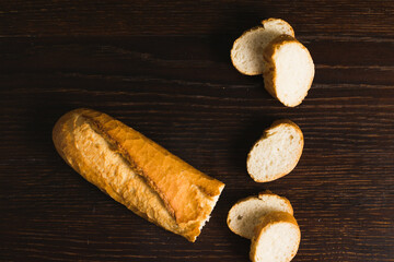 French baguette with an appetizing crust cut into pieces on a wooden background close-up