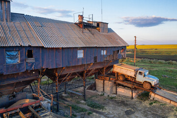 Fototapeta premium Volga region, harvest season. Mechanized threshing floor at the sunset light. Aerial view.