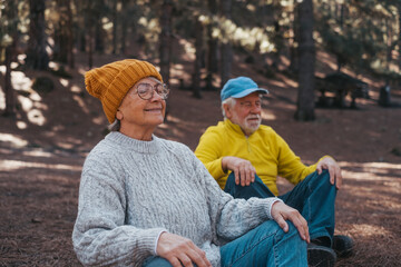 Head shot portrait close up of two old seniors middle age people meditating and relaxing in the mountain in the middle of the forest outdoors. Two mature persons having fun enjoying relax.