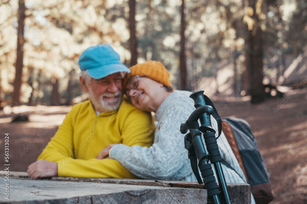 Wall mural Head shot portrait close up of cute couple of old middle age people having fun and enjoying together in the forest of the mountain at the table relaxing and resting..Mature woman hugging husband 