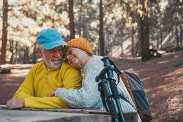 Head shot portrait close up of cute couple of old middle age people having fun and enjoying together in the forest of the mountain at the table relaxing and resting..Mature woman hugging husband 