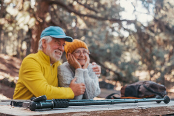 Head shot portrait close up of cute couple of old middle age people having fun and enjoying together in the forest of the mountain at the table relaxing and resting..Mature woman hugging husband 