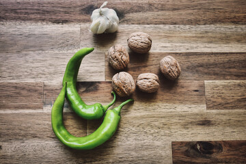 Top view of fresh green sweet peppers, a head of garlic and shelled walnuts on a wooden table.  Healthy eating food low carb ketogenic diet 