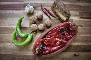 Roasted red peppers in a ceramic pot on a wooden table, accompanied by two slices of traditional...