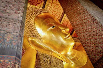 The golden face of reclining buddha statute at public temple Wat Phra Chetuphon or Wat Pho in...