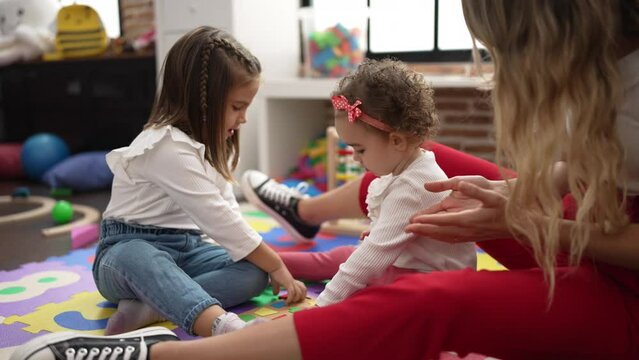 Teacher with girls playing with maths puzzle game and construction blocks at kindergarten