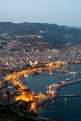 Obraz premium Beautiful portrait of Alanya Harbour and the Red Tower at night with the Taurus Mountains and Mediterranean Sea, Turkey.