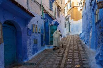 North Africa. Morocco. Chefchaouen. An old man dressed in a djellaba walking in a street of the medina