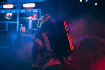 A firefighter taking equipment surrounded with a smoke.