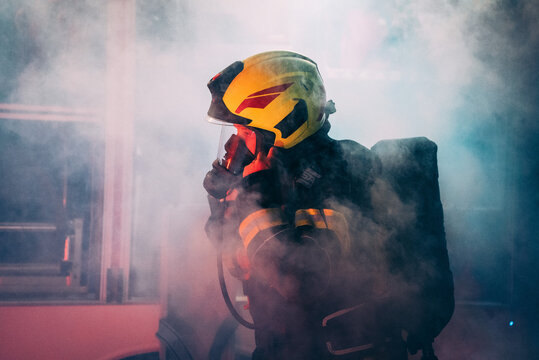 A firefighter taking equipment surrounded with a smoke.