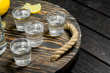 Vodka on a tray with lemon.