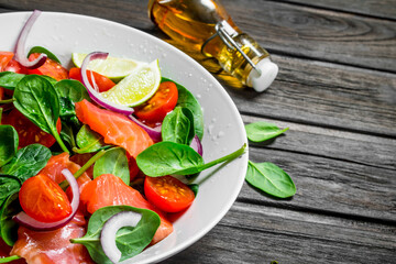 Fish salad. Salad with slices of salmon, tomatoes and spinach with lime juice.