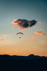 paraglider silhouette at sunset over the mountains