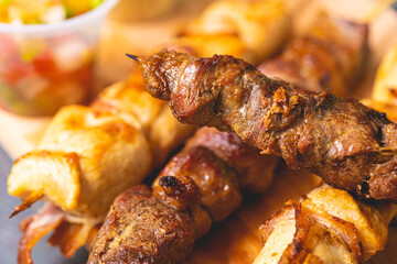 Churrasquinho brasileiro. Espetinhos com carne bovina e carne de frango com bacon sobre uma tábua...