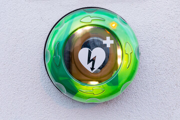 green lit Automated External Defibrillator, AED on a white wall