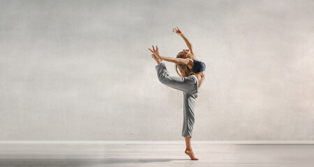 Inspiration - Female young dancer dances at the gray concrete background.