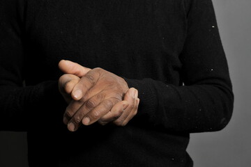 Fototapeta premium man praying to god with hands together Caribbean man praying on grey black background with people stock photo