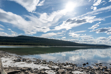 Picturesque summer day in northern Canada during July. Calm water with clouds and mountains reflection. 