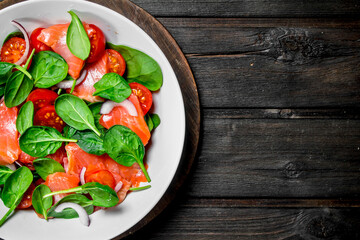 Fish salad. Salad with slices of salmon, tomatoes and spinach with lime juice.