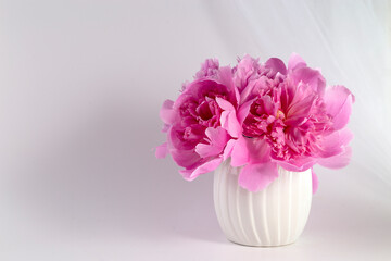 Pink peonies in a vase on a light background. Congratulations on Valentine's Day. Copy space