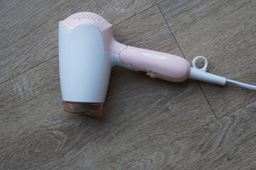 Fototapeta premium top view white and pink plastic hair dryer on wooden floor background, object, technology, decor, copy space