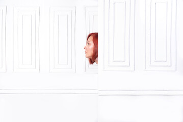 Fototapeta na wymiar woman's face peeking out from behind a white wall