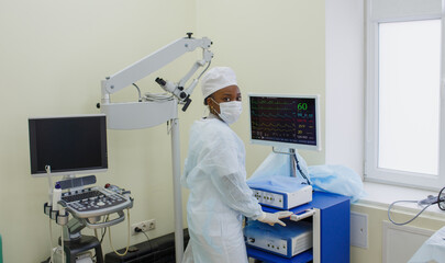 Naklejka premium an African-American nurse near the screen of artificial ventilation equipment. Hospital, surgical operating room