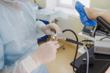 a male doctor in a white coat and rubber gloves, holding a colonoscope in a cookie, is preparing...