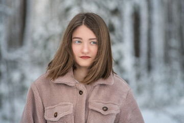 Portrait of a young beautiful girl in the winter forest.