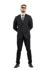 Secret agent or guard with hands behind back wearing sunglasses.Full body length portrait isolated...