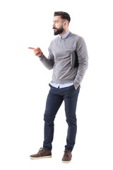 Confident young business man with documents pointing finger at copyspace. Full body length portrait...