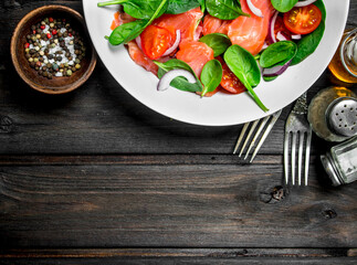 Fish salad. Salad with slices of salmon, tomatoes and spinach with lime juice.