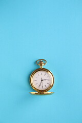 Golden pocket watch on a blue background.