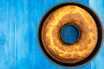 Homemade cake with cocoa in a mold on a rustic wooden background.
