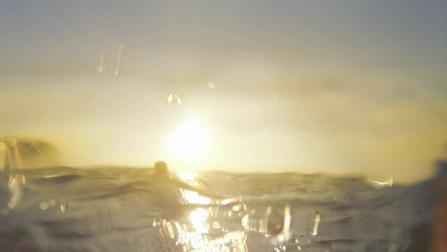 Drowning man looking for help from lifeguard on beach at sunset, slow motion