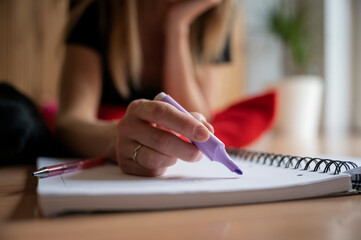 Low angle closeup view of female hand about to highlight something in her notebook