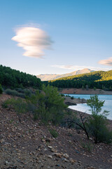 Beautiful landscape of a lake surrounded by greenery mountains and trees under a blue sky with amazing clouds at sunset, El Vado, Guadalajara, Spain