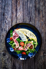 Tasty salad - prosciutto crudo, melon and fresh vegetables on wooden table
