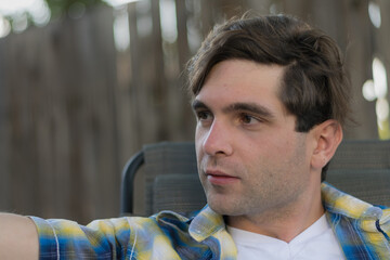 A young white man outdoors in a shady backyard setting.